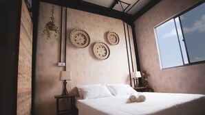 Une chambre avec un grand lit, une plante suspendue et trois assiettes décoratives accrochées au mur.