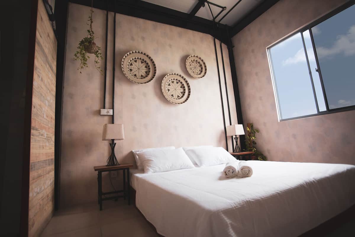 Ein Schlafzimmer mit einem großen Bett, einer hängenden Pflanze und drei dekorativen Wandtellern.