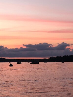 A sunset over a body of water with several boats. - Blue Moon Resort and Motel (Hill City)