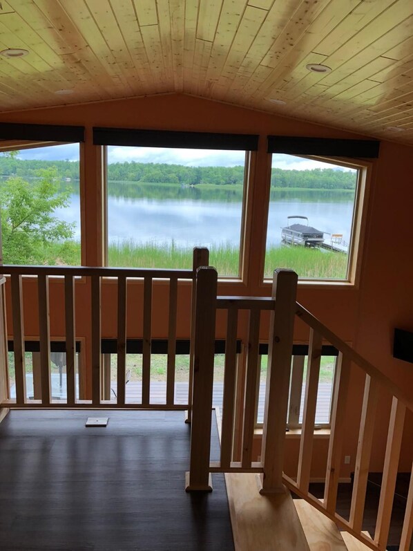 A cabin with a wooden deck and large windows overlooking a lake.