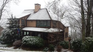 A two-story house with a steeply pitched roof, surrounded by snow-covered trees and bushes. - Rustic farmhouse on Appalachian  Ski Mountain (Blowing Rock)