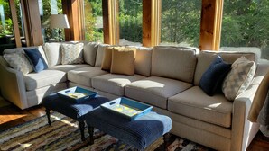 A beige sectional sofa with patterned cushions, a blue ottoman with trays, and a striped rug. - Rustic farmhouse on Appalachian  Ski Mountain (Blowing Rock)