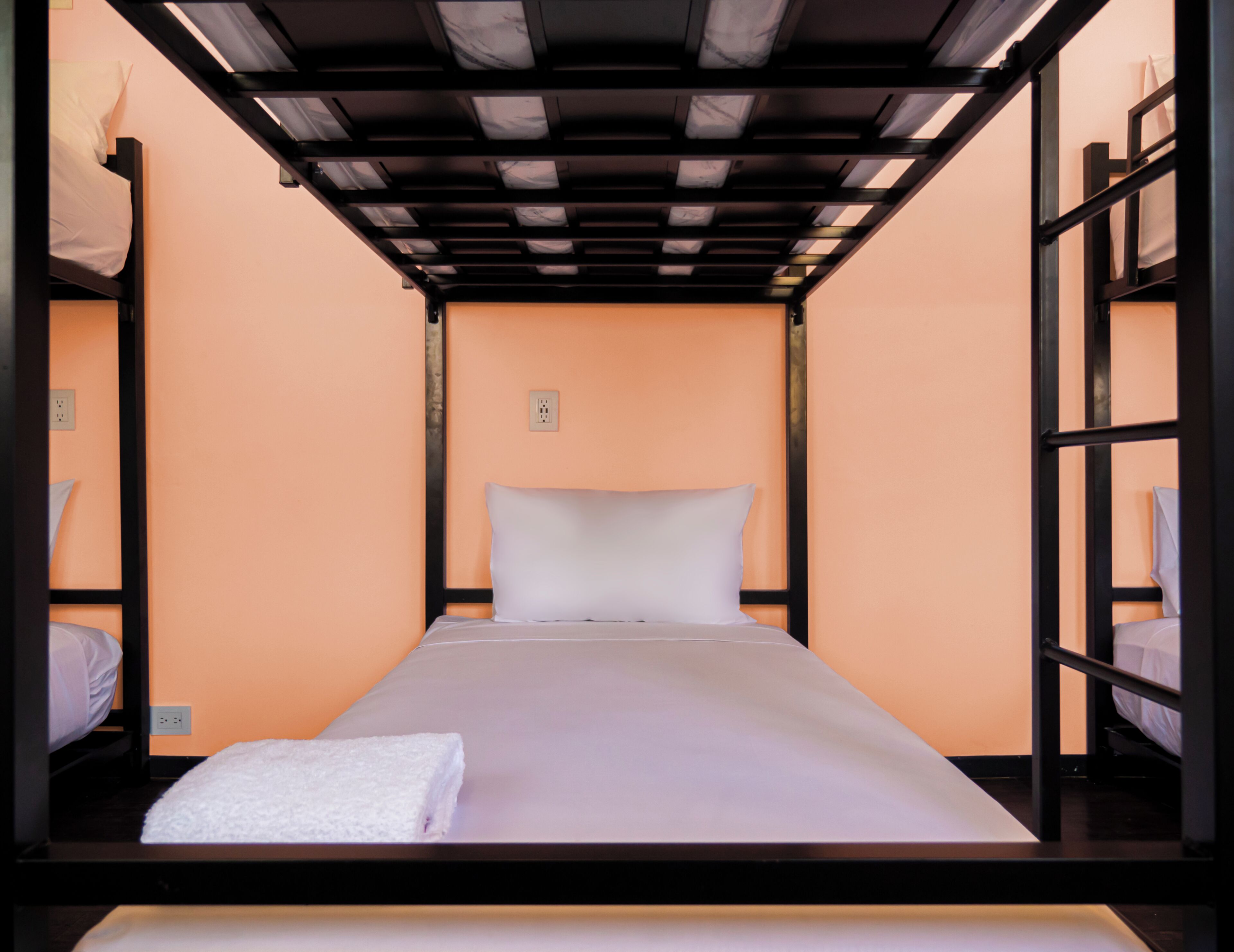 A bunk bed room with a single bed, a white pillow, and a white towel on the floor.