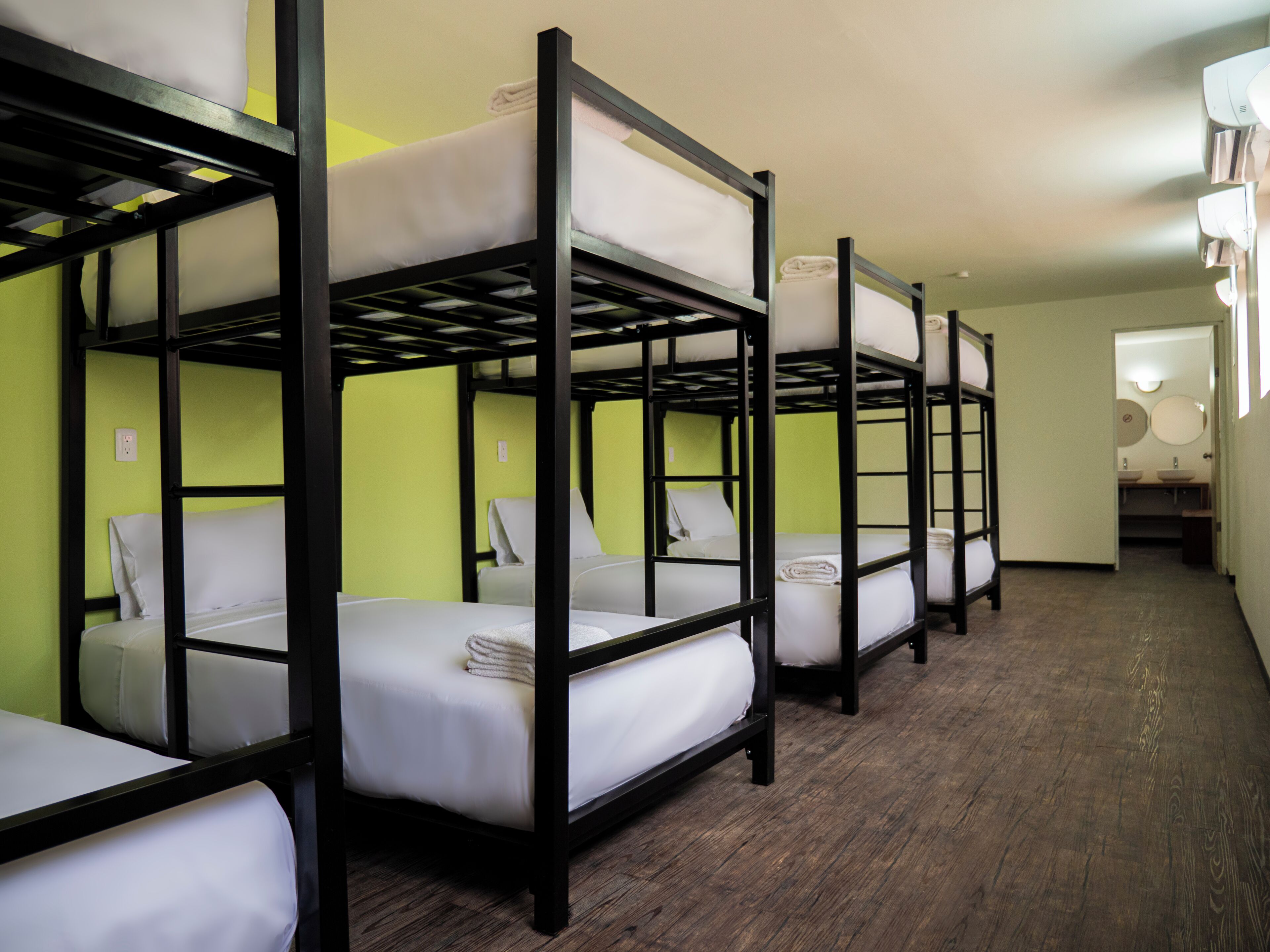 Bunk beds in a room with a wooden floor and a green wall.
