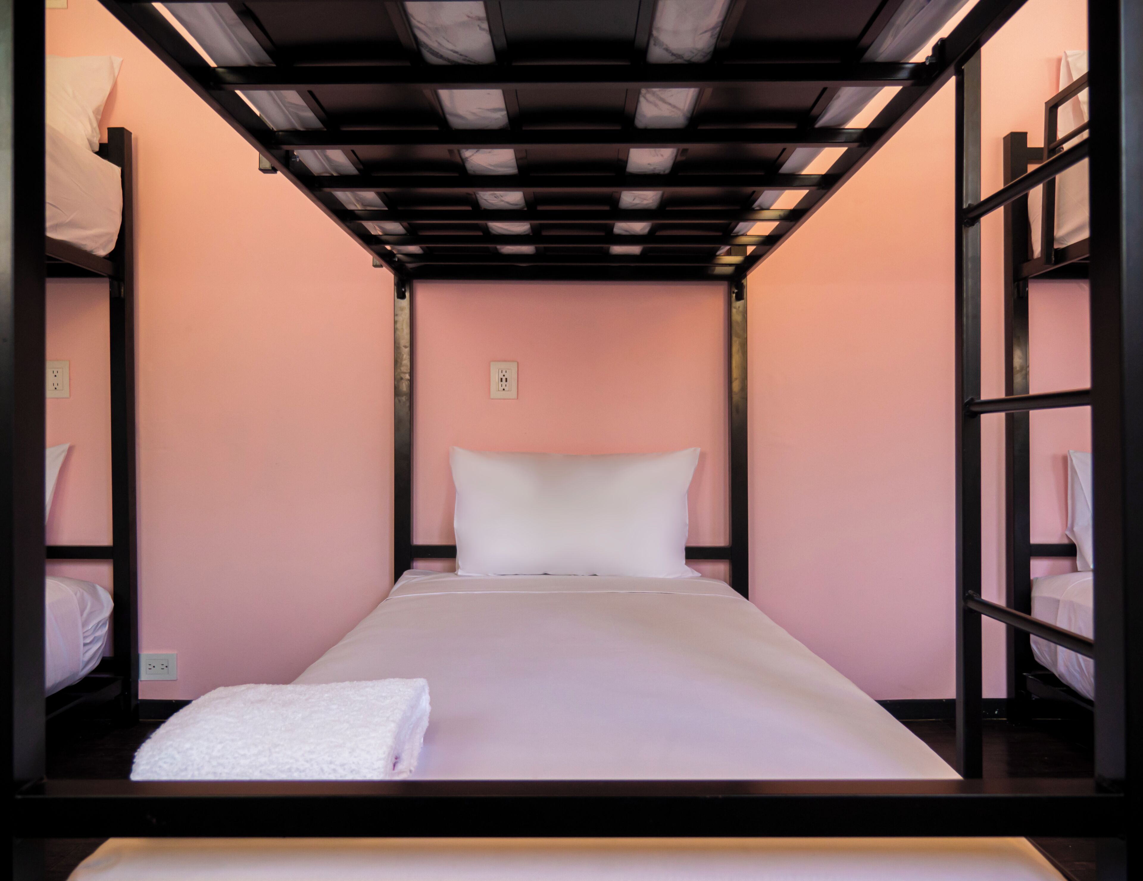 A bunk bed room with a single bed, a white pillow, and a white towel.