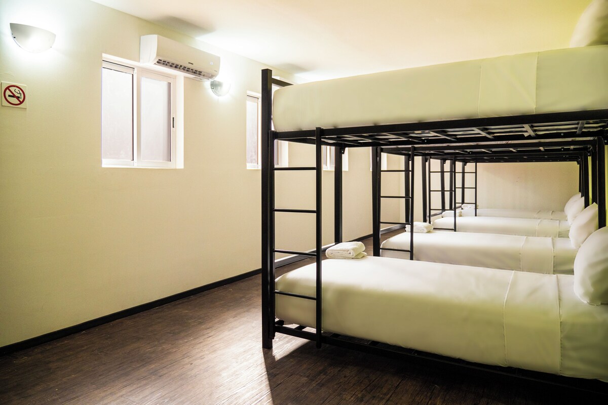A bunk room with a window, air conditioning unit, and a no-smoking sign.