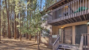Une cabane à deux étages dotée d’un balcon, entourée de grands pins.