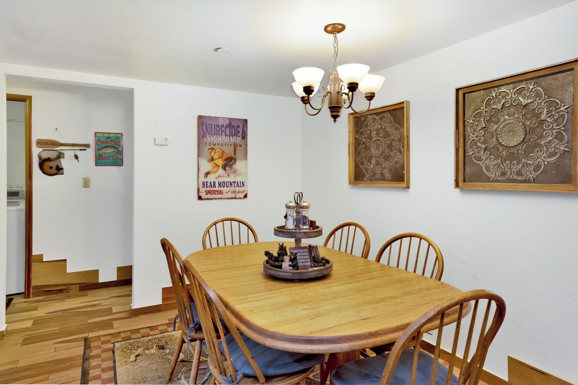 Ein Essbereich mit Holztisch und Stühlen, einer Chandelier und Wanddekoration.