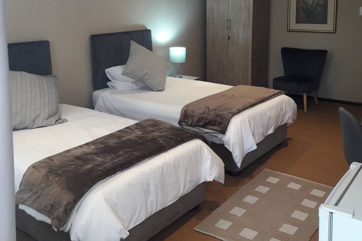 Ein Hotelzimmer mit zwei Betten, einem Kleiderschrank, einem Stuhl und einem Schreibtisch.