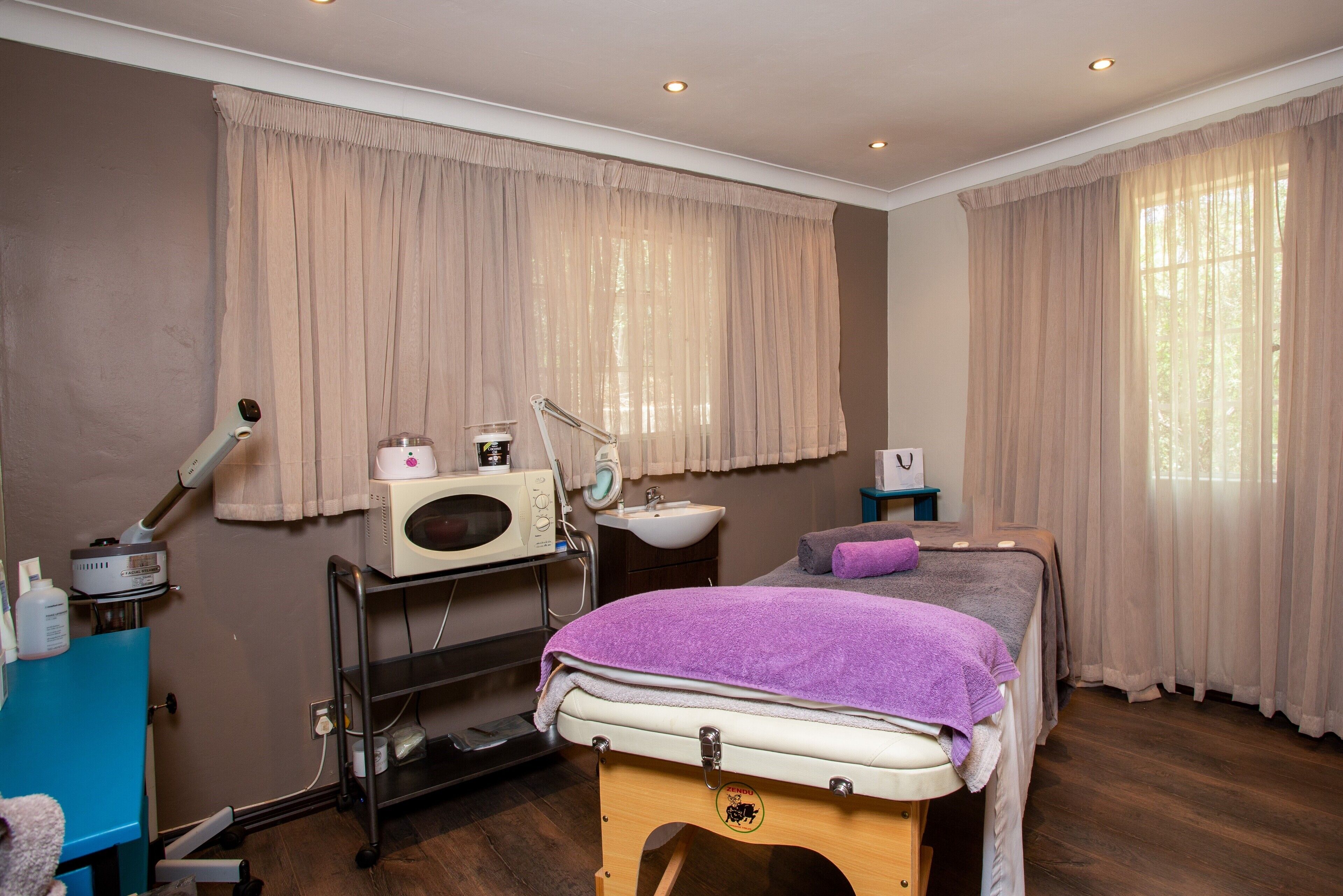 A room with a bed, a sink, a massage table, and a hairdryer.
