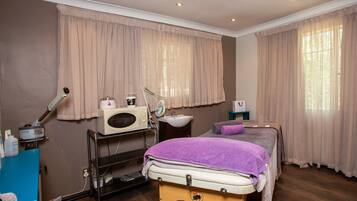 A room with a bed, a sink, a massage table, and a hairdryer.