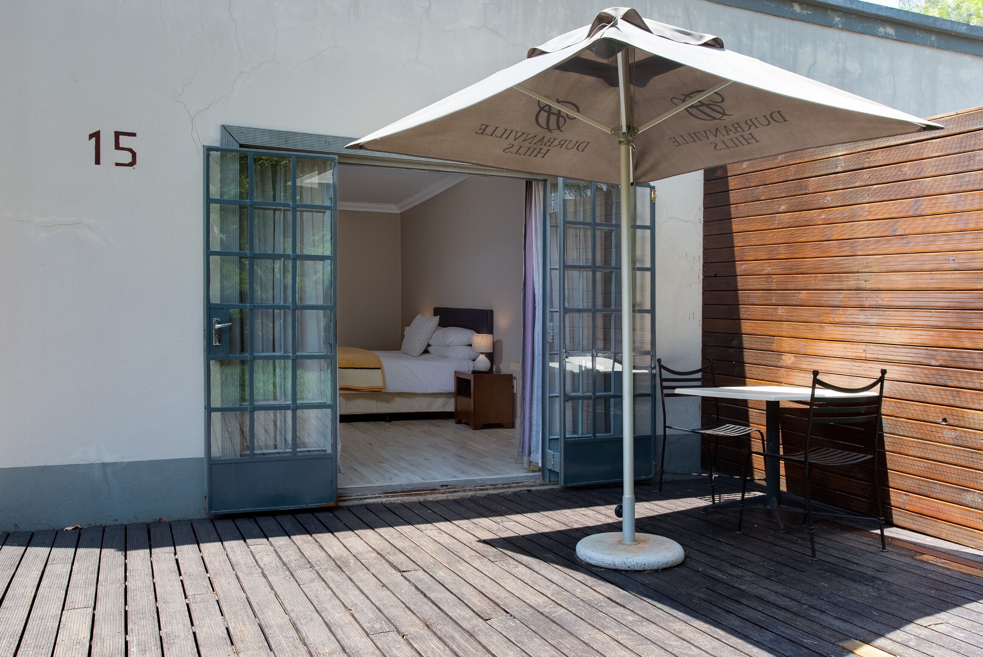 A room with a bed, a table with chairs, and an umbrella.