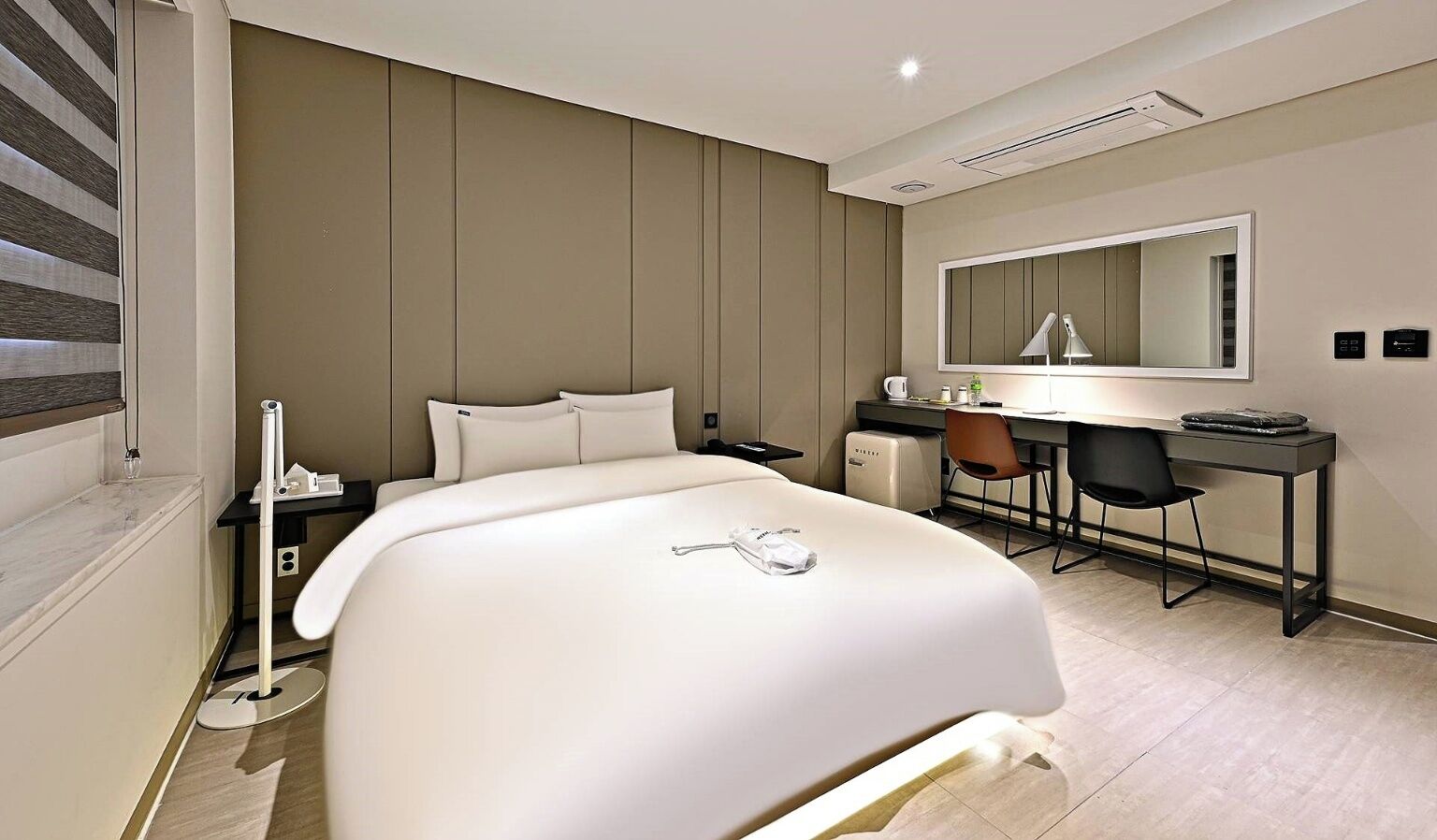 Une chambre d’hôtel moderne, dotée d’un grand lit, d’un bureau et d’une chaise.