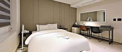 Une chambre d’hôtel moderne, dotée d’un grand lit, d’un bureau et d’une chaise.