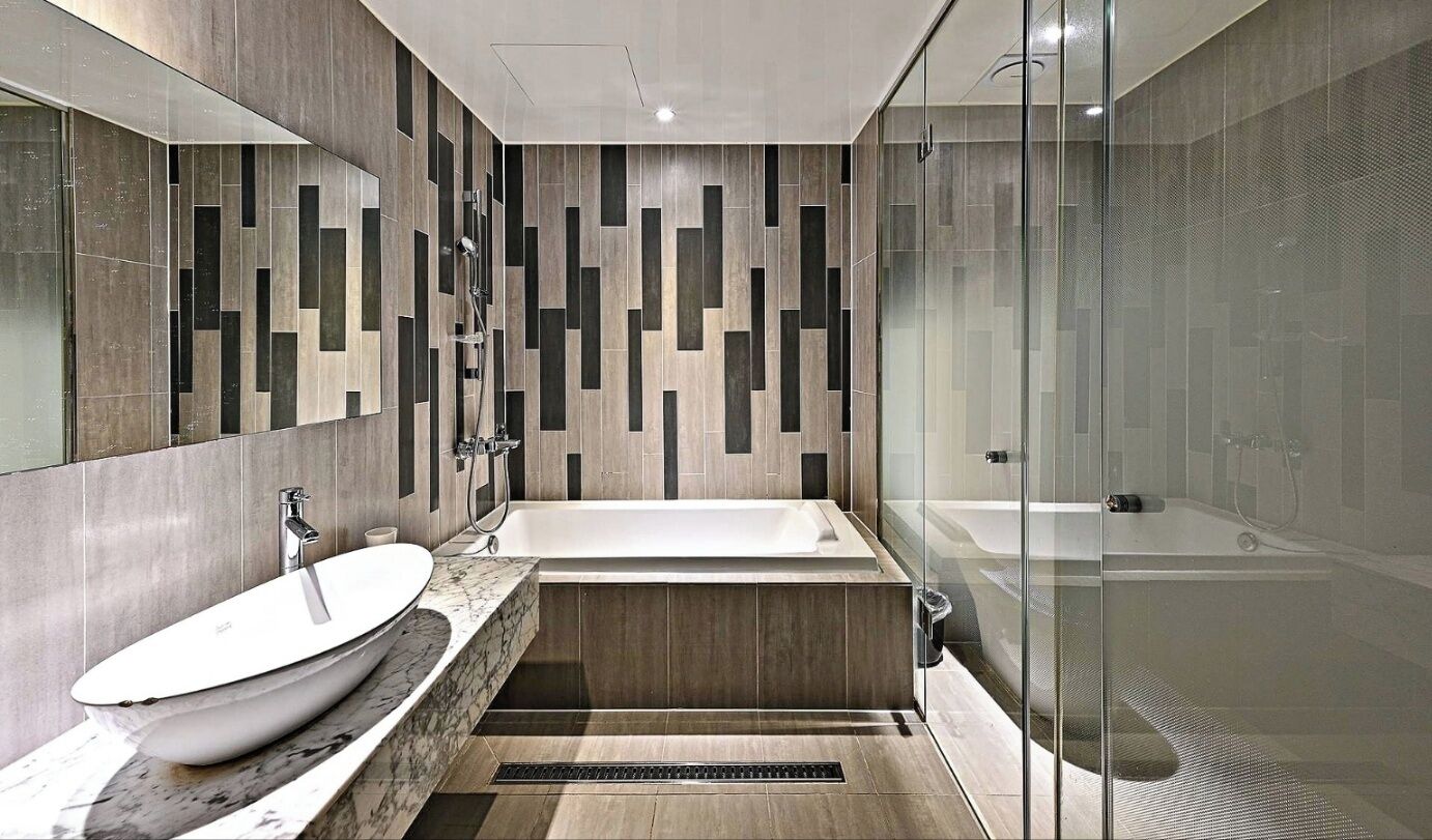 Un baño moderno con una bañera independiente, un espejo grande y una zona de ducha con paredes de cristal.