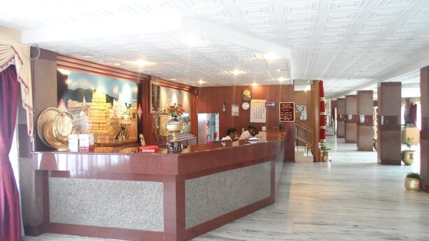 Un vestíbulo de hotel con una recepción, suelo de mármol y un gran mural de un edificio.