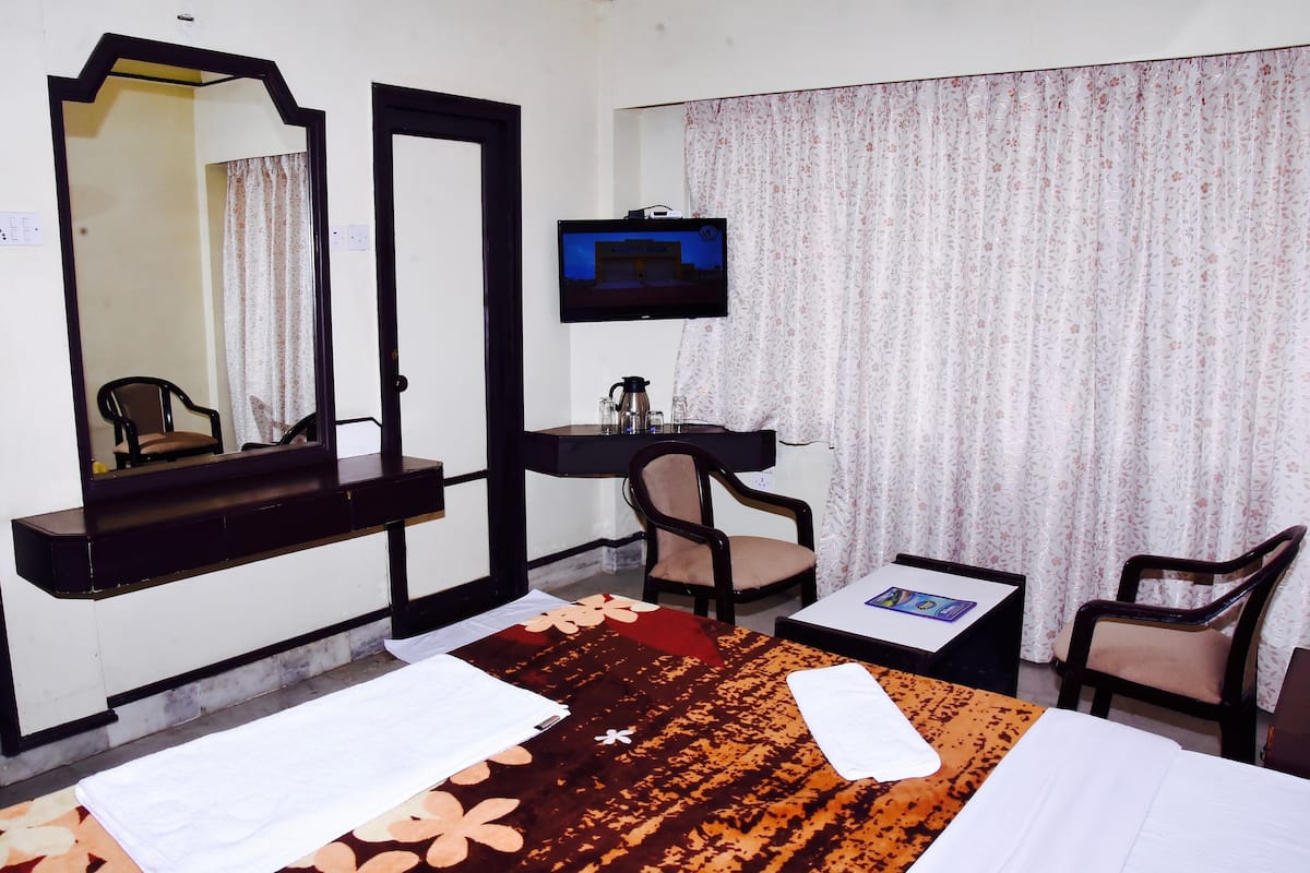 Een hotelkamer met een bed, een bureau, een stoel, een televisie en een spiegel.