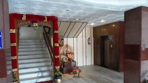 Una escalera con un arco floral rojo que lleva a un cuarto con una estatua y un extintor.