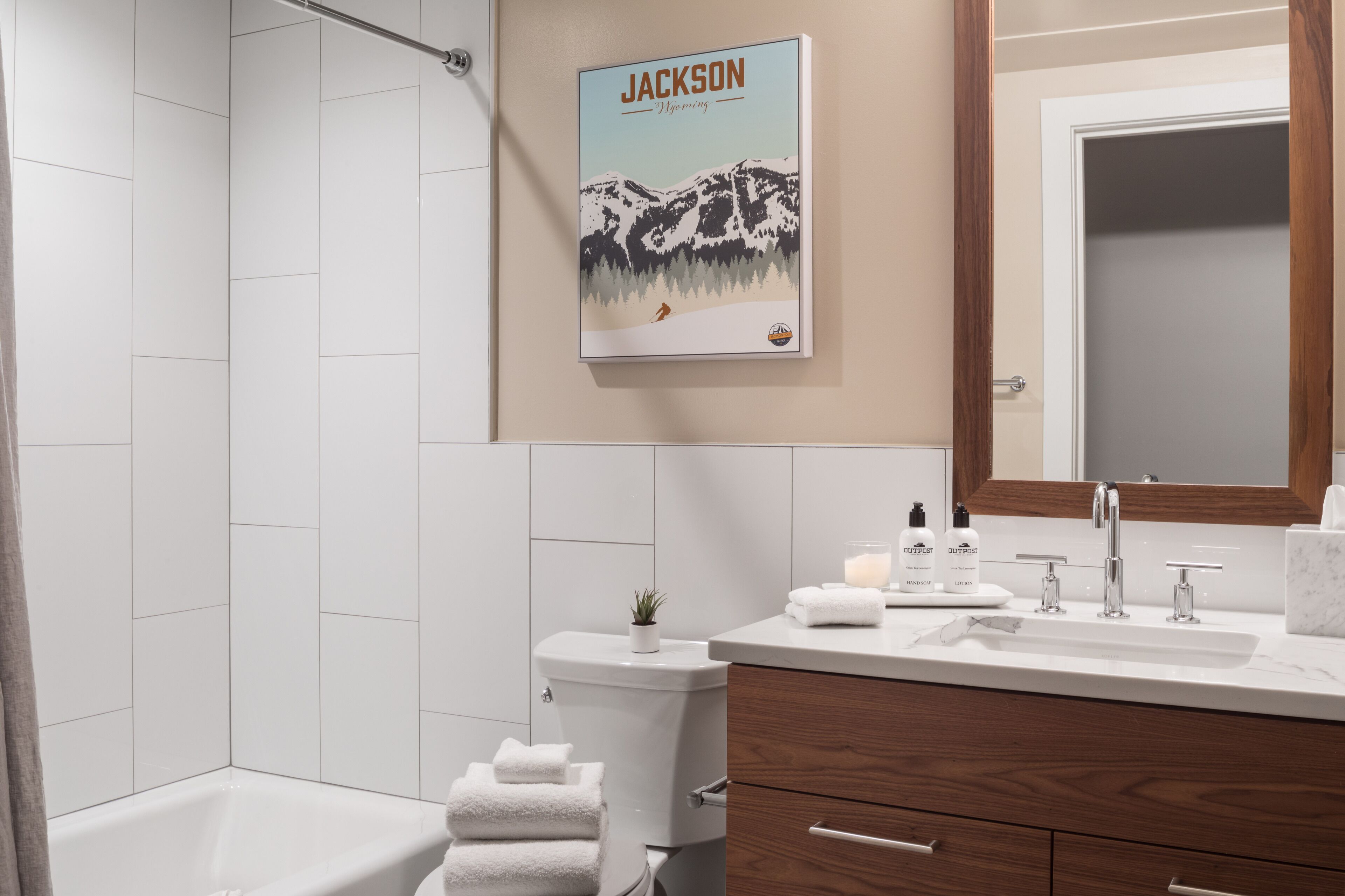 Een moderne badkamer met een douche, toilet en wastafel. Aan de muur hangt een poster en boven de wastafel een spiegel.