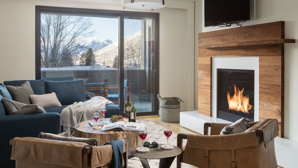 Una sala de estar moderna con chimenea, un sofá, una mesa de centro y un televisor montado en la pared.