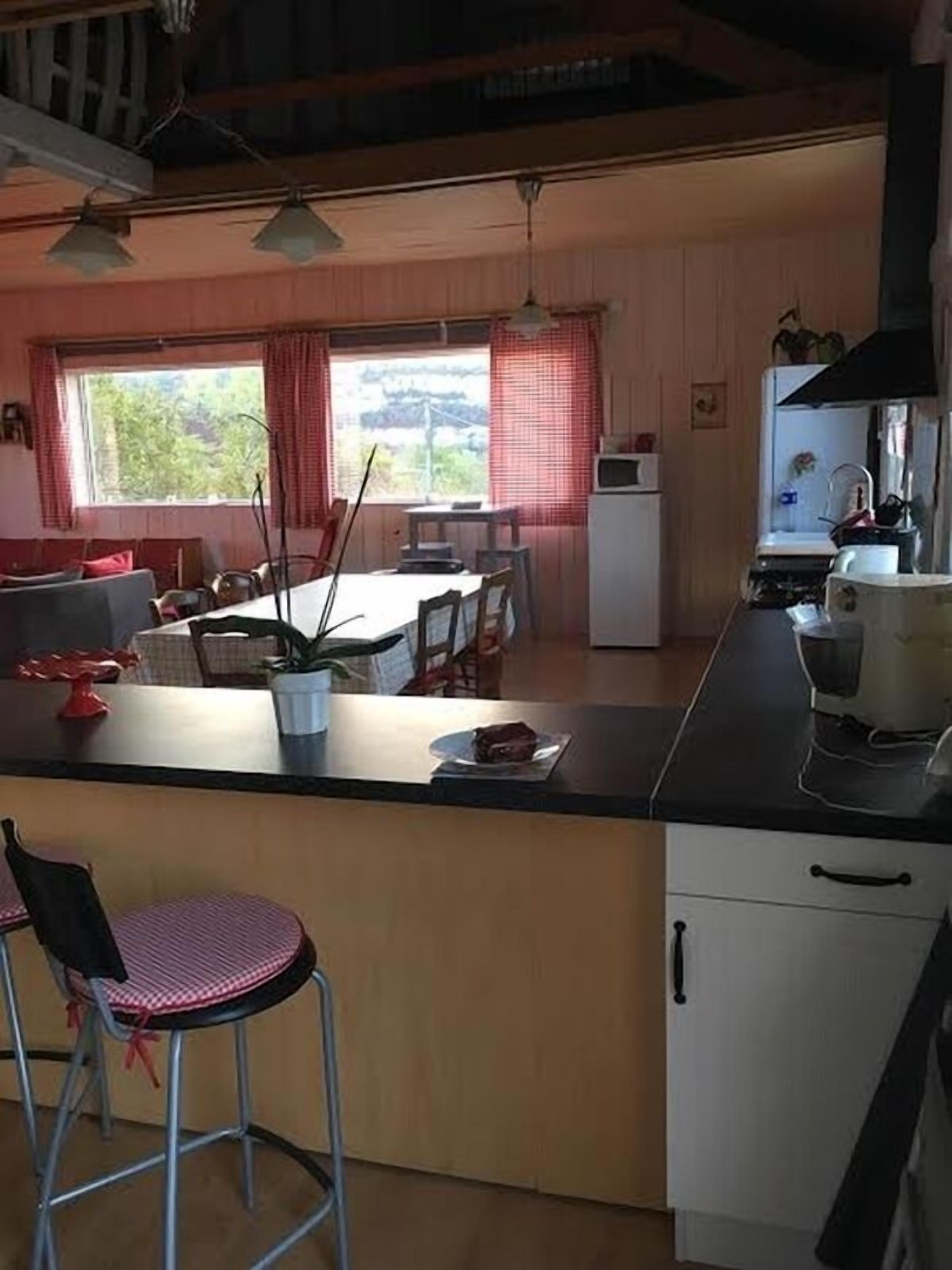 A compact kitchen with a dining area, featuring a central island, a refrigerator, and a microwave.