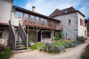 Ein rustikales Steinhaus mit einem Holzbalkon und einer Treppe, die zum Eingang führt.