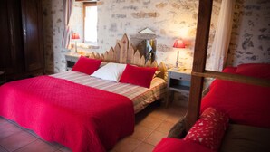 Un dormitorio con una cama grande, dos mesitas de noche, un cabecero de madera y una pared de piedra.