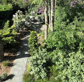 Stroll through the beautifully maintained garden, lined with vibrant flowers and shrubs, and a bench for a peaceful retreat.