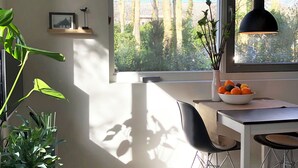 A modern kitchen with a dining area, large windows, and a view of trees. - Studio OAK, modern 2-p-residence with private garden, near village, sea and dune (Bergen)
