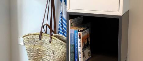 A room with a wooden drying rack, a wicker basket, and a bookshelf containing books and a sign.