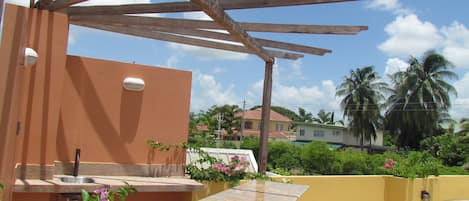 Uma varanda com vista para uma área residencial, incluindo casas e palmeiras.