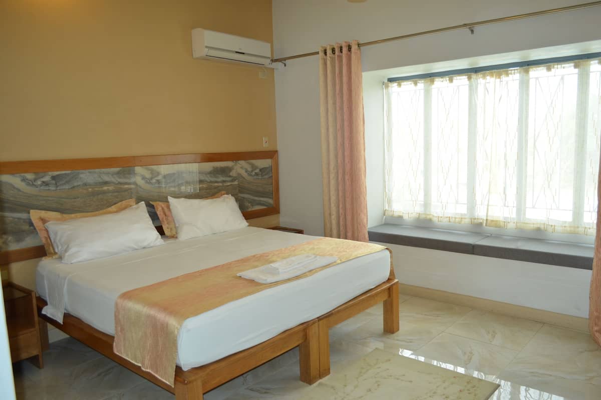 A bedroom with a large bed, a headboard with a marble-like design, a window with curtains, and a built-in bench at the foot of the bed.