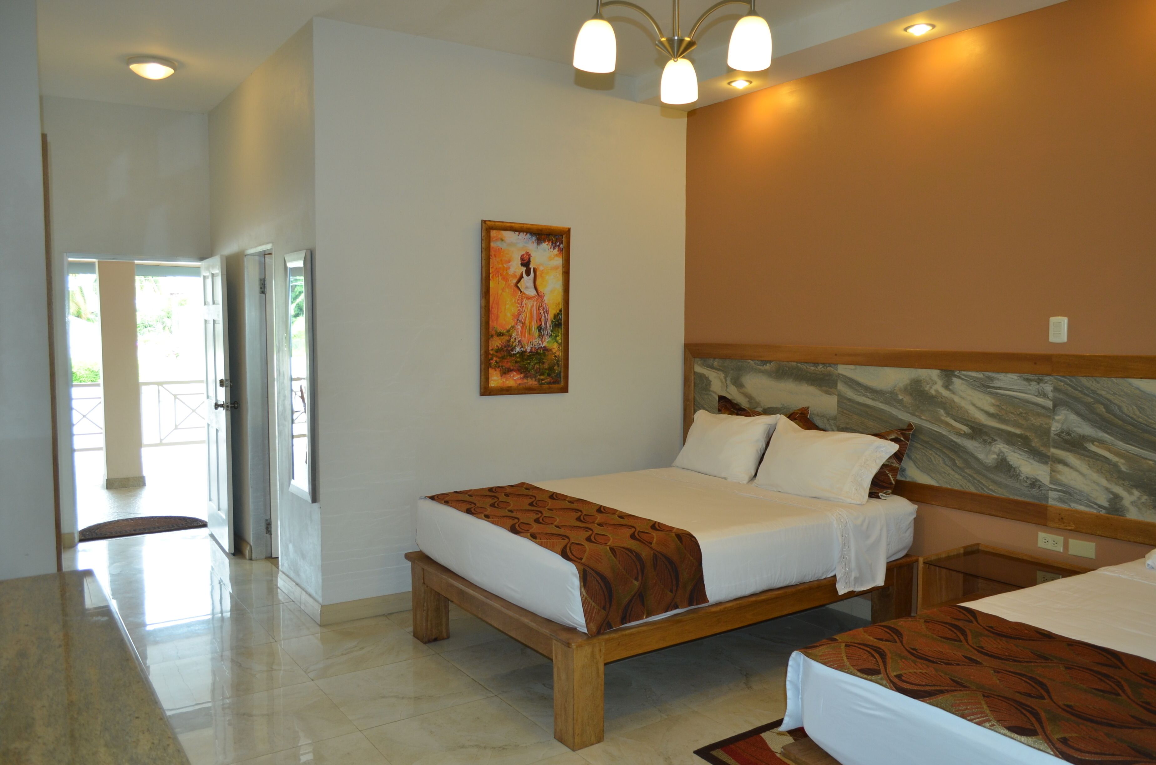 A hotel room with a wooden bed, a painting on the wall, and a view of the outdoors.
