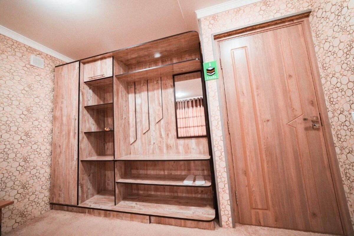 A room with a wooden wardrobe, a door, and a patterned wall.
