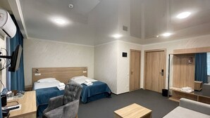 A hotel room with two beds, a desk with a chair, a sofa, a small wooden table, and a mirror. -  Reikartz Kokand (Kokand)