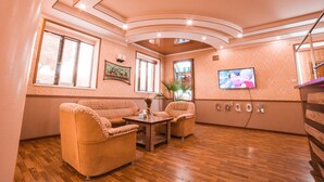 A room with a wooden floor, two sofas, a table, and a TV on the wall. -  Reikartz Kokand (Kokand)