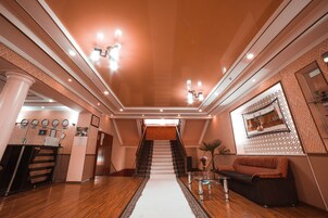 A spacious lobby with a central staircase, a reception desk, and a seating area.