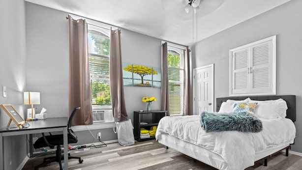 A bedroom with a bed, desk, chair, and a window with curtains. - 30-Night Minimum Studio Near Main Street (St Charles)