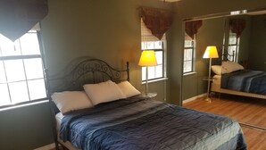 Un dormitorio con una cama, dos lámparas de noche, un espejo y una ventana.