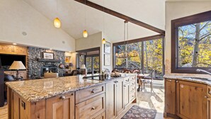 A spacious kitchen with granite countertops, wooden cabinets, and a stone backsplash. - Grand Hyatt|Bright & Airy Centrally Located Condo (Vail)