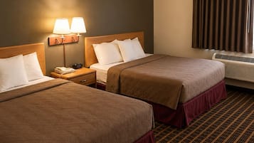 A hotel room with two beds, a nightstand with a lamp, a telephone, and a window with curtains.