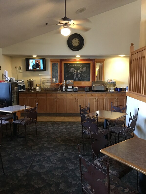A restaurant with wooden cabinets, a chalkboard menu, and a television mounted on the wall. - Moose Lake Lodge & Suites (Moose Lake)