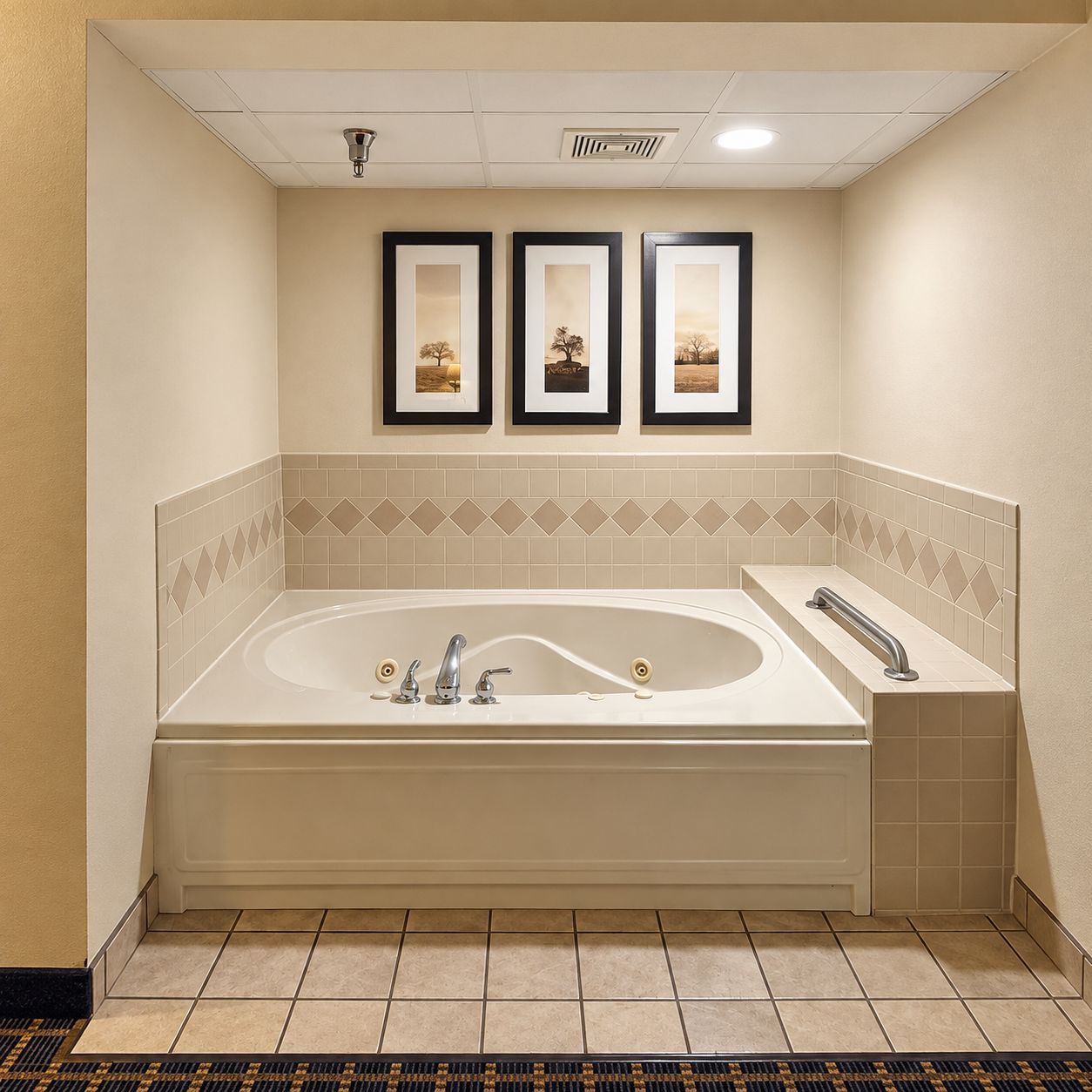 A bathroom with a freestanding bathtub, a handrail, and three framed pictures on the wall.