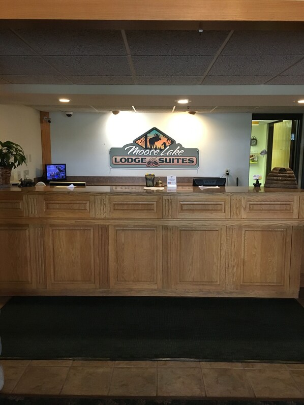 Un comptoir d’accueil avec une enseigne indiquant « Moose Lake Lodge Suites ».