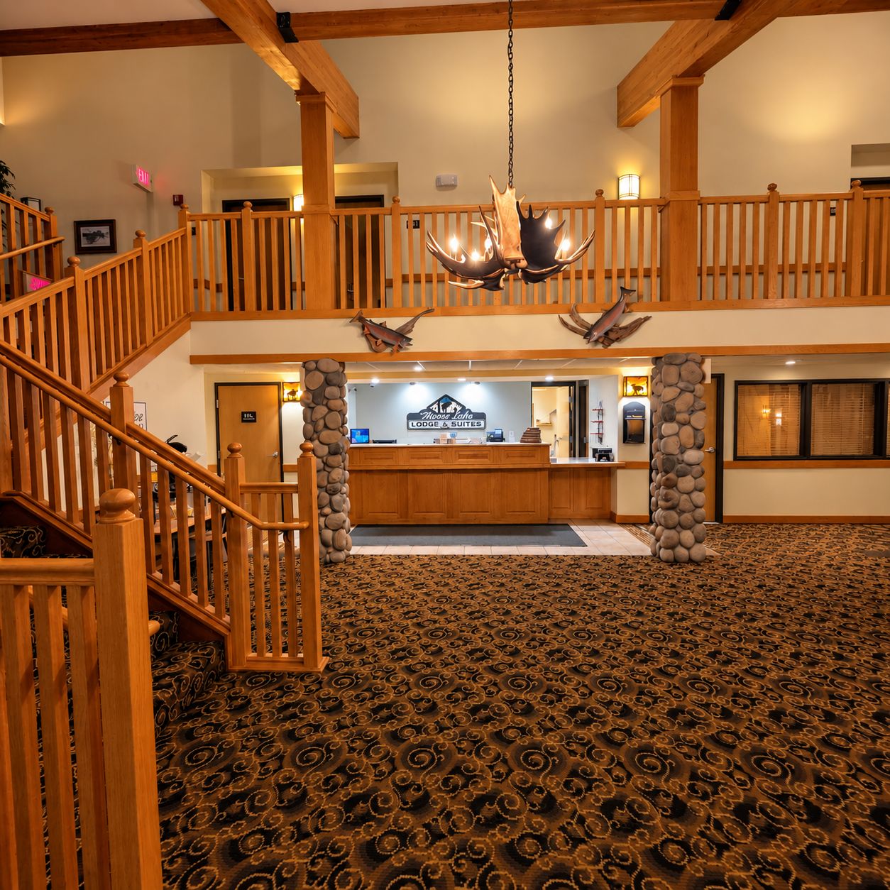 A hotel lobby with a grand staircase, a reception desk, and a chandelier.
