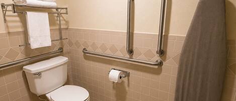 Une salle de bain équipée de toilettes, de barres d'appui, d'un porte-serviettes et d'un support à papier toilette.
