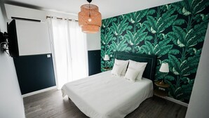 A bedroom with a bed, a nightstand, a lamp, a wall-mounted air conditioner, and a window with curtains.