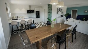 A modern kitchen with white cabinets, a wooden dining table, and a checkered floor.