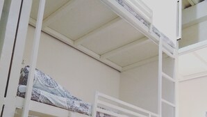 A bunk bed room with a ladder, a patterned floor, and a plain wall.