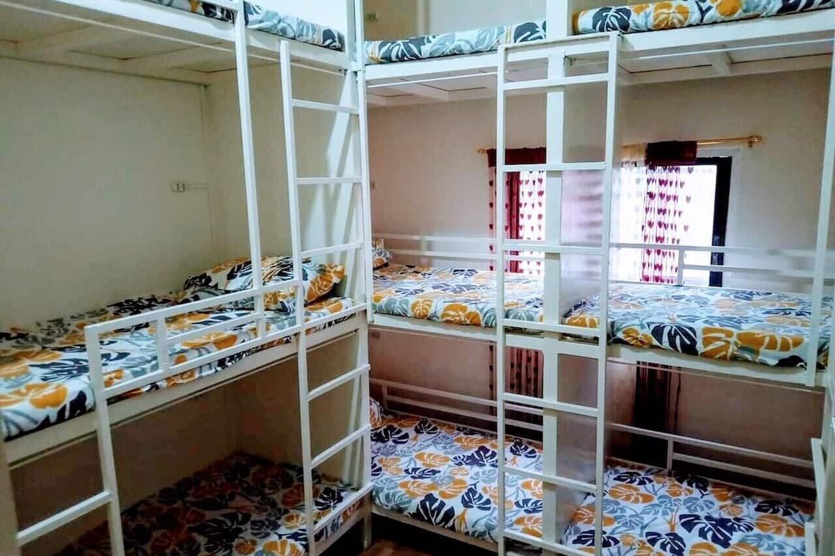 Une chambre avec un lit superposé, dotée de draps à motifs floraux et d’une échelle.